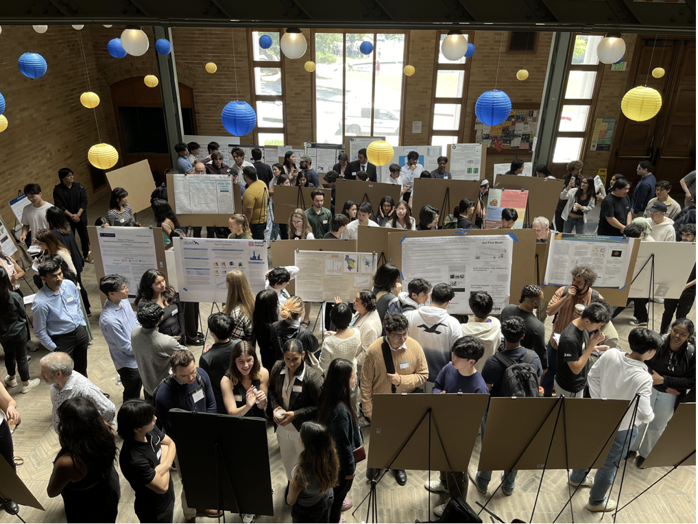 Student presenting science posters in an auditorium