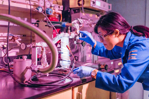 a student wearing safety glasses is working with complex machinery