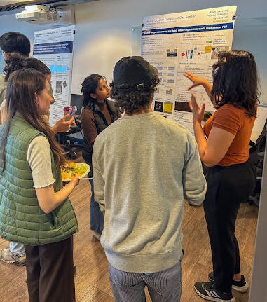 Students viewing a research poster being presented by another student