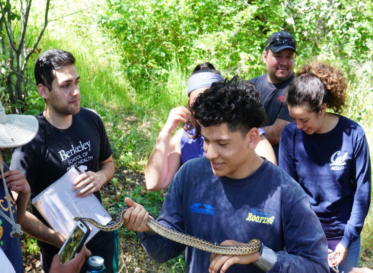 students in the woods holding a snake