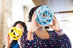 students holding plastic sculptures in front of their faces