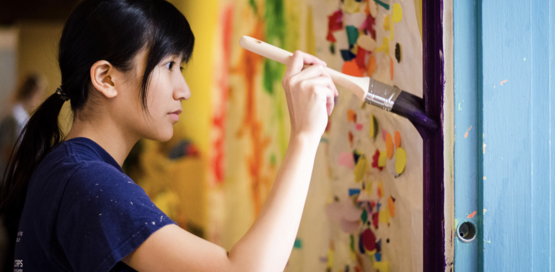 a photograph of a student painting a large canvas